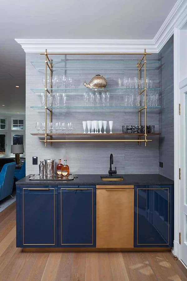Custom navy blue and brass kitchen bar cabinets with glass shelving