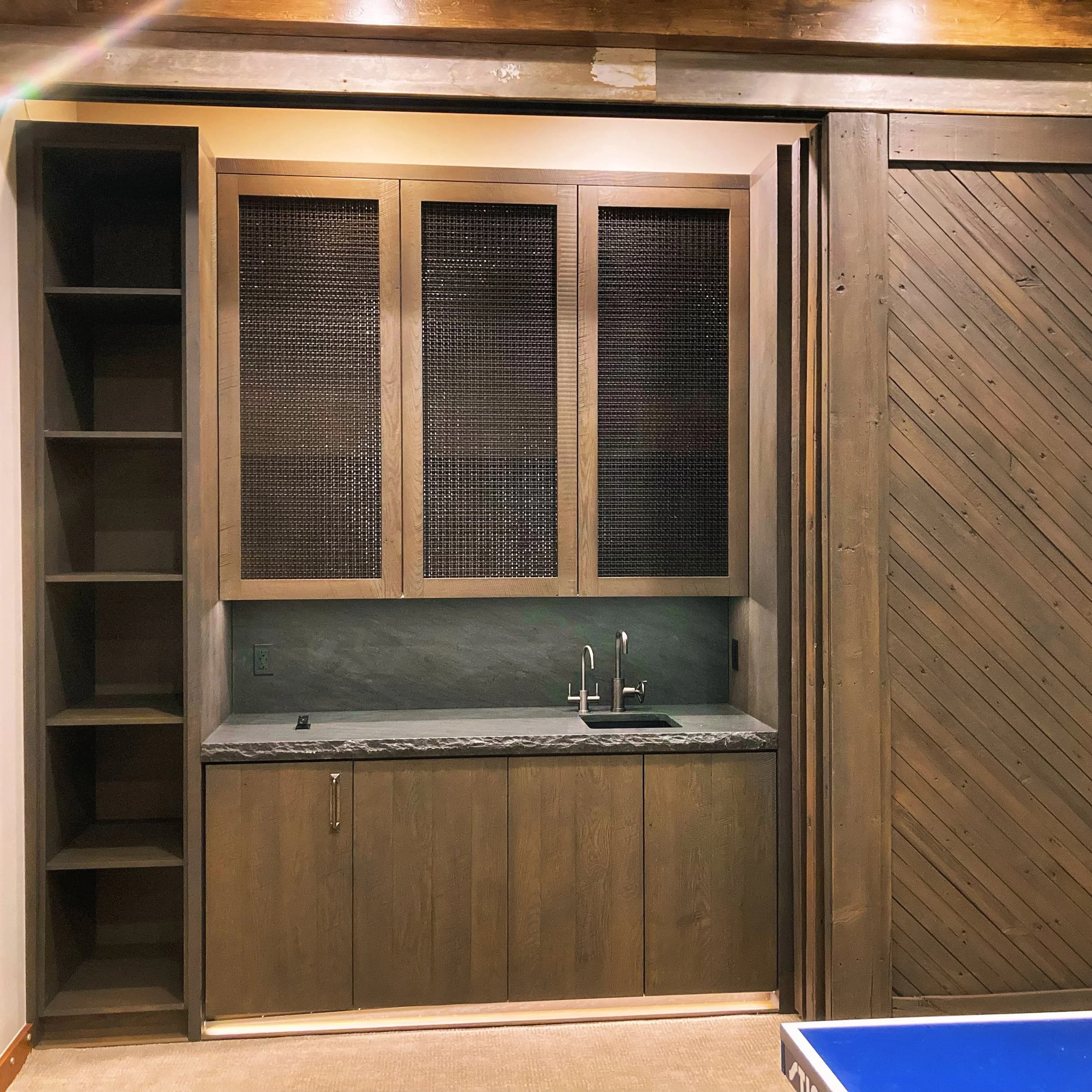Custom cabinet installation with mesh door panels and concrete countertop